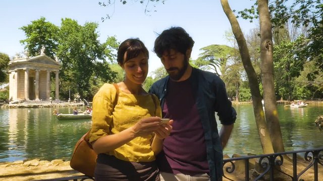 Young Couple Taking Selfie by a Pond in a Park in Rome