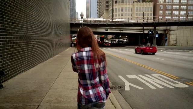 Young woman talking on smart phone in modern city. Back view of woman in casual dress walking and talking on mobile phone. Urban city lifestyle. Woman walking in street chicago