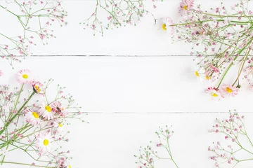 Rolgordijnen Flowers composition. Floral frame made of pink gypsophila flowers and daisy flowers on white wooden background. Flat lay, top view, copy space © Flaffy