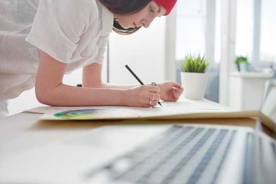 Young female illustrator working on sketches at home office