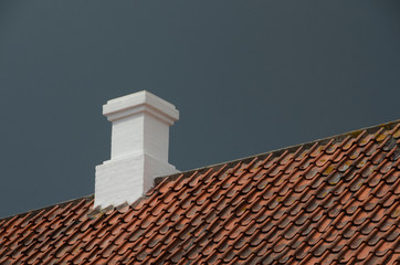 White chimney on a red tile roof.