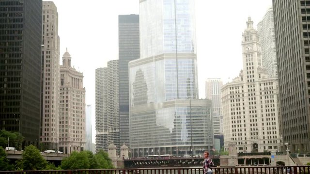 Happy smiling woman standing on bridge over river in big city and waving. Young beautiful woman stand on bridge. City buildings. Chicago city. Chicago skyline