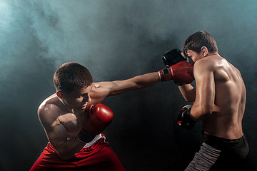 Fototapeta na wymiar Two professional boxer boxing on black smoky background,