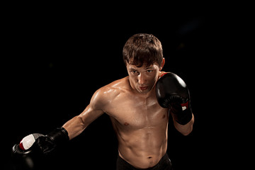 Male boxer boxing in punching bag with dramatic edgy lighting in a dark studio