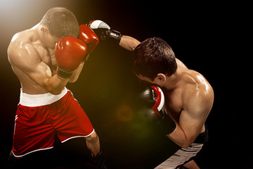 Fototapeta na wymiar Two professional boxer boxing on black background,