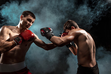 Two professional boxer boxing on black smoky background,
