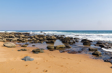 Fototapeta na wymiar Beach Against Rocky Ocean Shoreline and Blue Sky Landscape