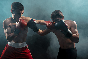 Two professional boxer boxing on black smoky background,