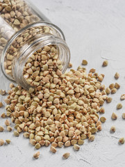 Raw green buckwheat in bank on gray background