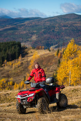 Man on quad bike in the mountains on a blurred background mighty mountains and forests in the autumn sunny day © anatoliy_gleb