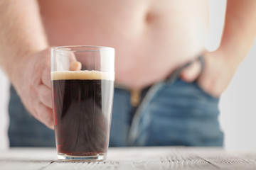 fat man's with fatty tummy and holding cola grass that not good for health