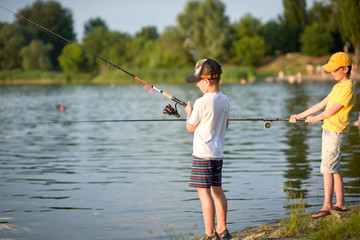 Two boys are fishing on the beach at sunset