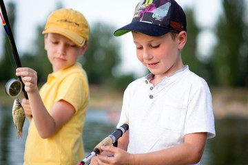 Two boys are fishing on the beach at sunset