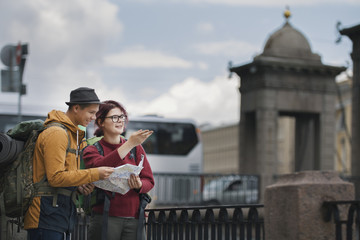 Young tourists check the route on the navigator city map