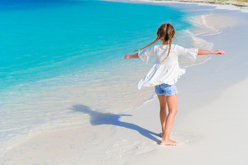 Fototapeta na wymiar Happy adorable little girl walking on the white beach