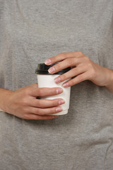 A disposable white glass in the hands of a girl