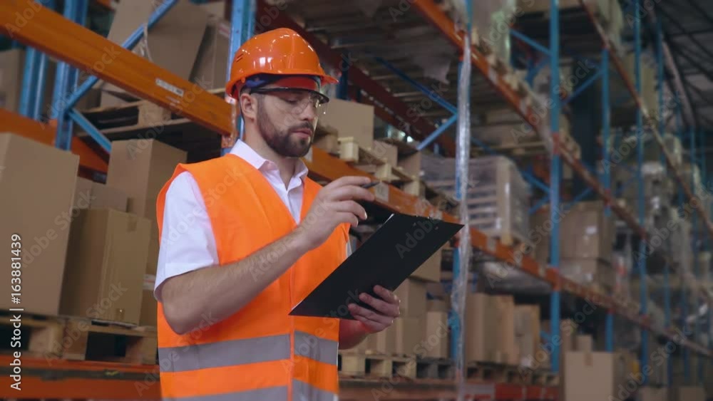Poster handsome young employee working at warehouse. worker wearing high visibility clothing and a hard hat