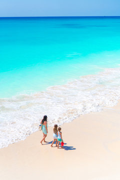 Adorable little girls and young mother on white beach. View to the family and ocean from above