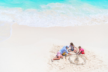 Father and little daughters making sand castle at tropical beach © travnikovstudio
