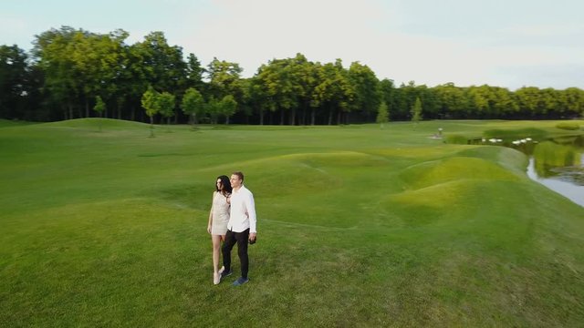 Aerial View Of Young Couple Walking In Summer Park, Circling Drone Shooting Man And Woman Outdoors
