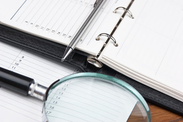 pen, magnifying glass and diary