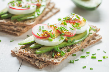 Closeup of sandwich with avocado, radish and eggs
