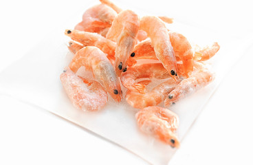 Shrimp are on the small glass dish on a white background.