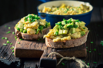 Fried eggs with avocado and chive on wooden table