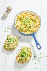 Fried eggs with avocado and chive on white table
