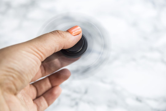 Spinner in a female hand on a background of a marble working table