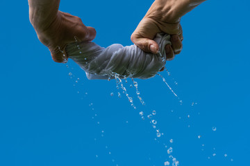 Squeezing of wet cloth against blue sky.