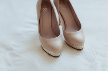 Bride wedding shoes with high heels and silver brilliant earrings on sheep's clothing