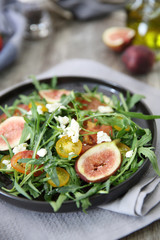 Fresh salad with arugula tomato and cheese on wooden background