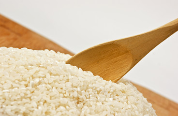 raw rice and wooden spoon on bamboo board