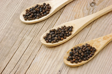 Black pepper in wooden spoon on the old board