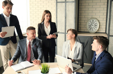 Brainstorm. Group of business people looking at the laptop together. One business woman looking at camera.
