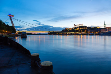 Naklejka premium Bratislava, New Bridge, Castle, Cathedral during dusk from a boat on river Danube