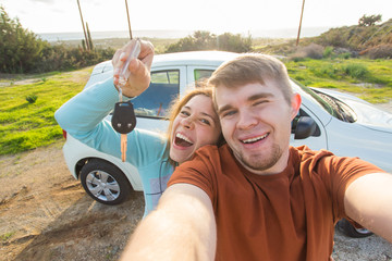 Young funny couple with keys to new car outdoor