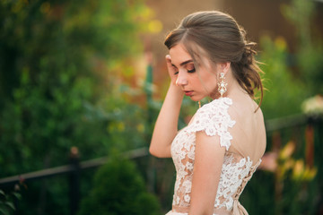 Naklejka premium Young girl in wedding dress in park posing for photographer. portrait