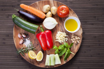 Ingredients vegetables for soup with pesto sauce and basil on a wooden plate.