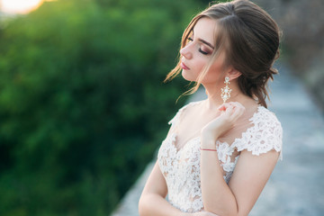 Young girl in wedding dress on city background at sunset.