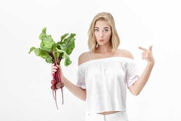 Beautiful blond woman is pointing at beetroot with green leaves on white background. Health and vitamins