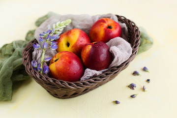 Peaches in a basket decorated with flowers on a light background