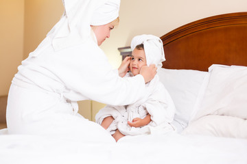 mother and daughter in head towels after shower in bed at home
