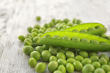Fresh green peas on white wooden background