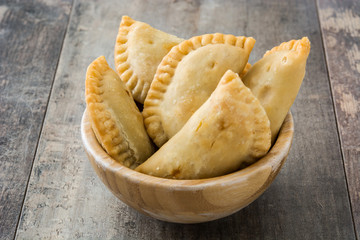 Typical Spanish empanadas in bowl on wooden table
