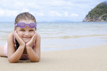 Happy little girl lying on the sand on the beach Female preschooler kid