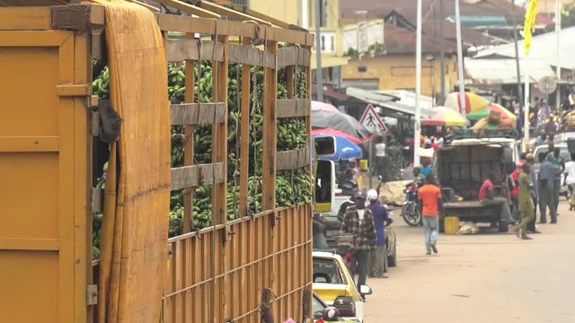 Market village town centre in Guinea West Africa with traffic and cargo lorry full of bananas