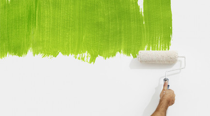 paint roller hand painting green color isolated on blank white wall background, ecology concept