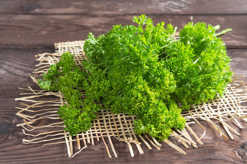 Fragrant green parsley ingredients for vegetarian dietary salad on a dark wooden background with copy space